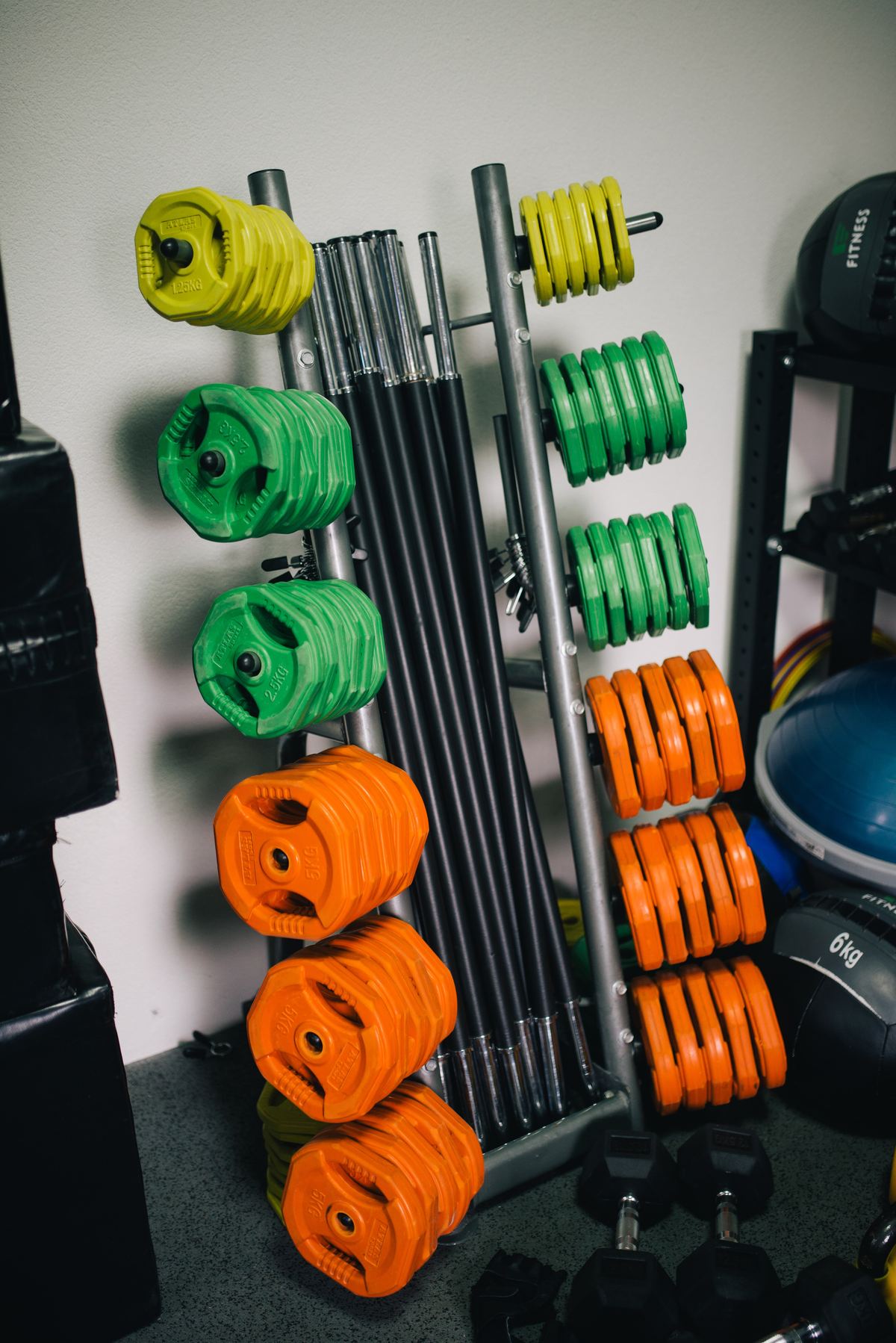 Colour-coded weight plates stacked on a storage rack