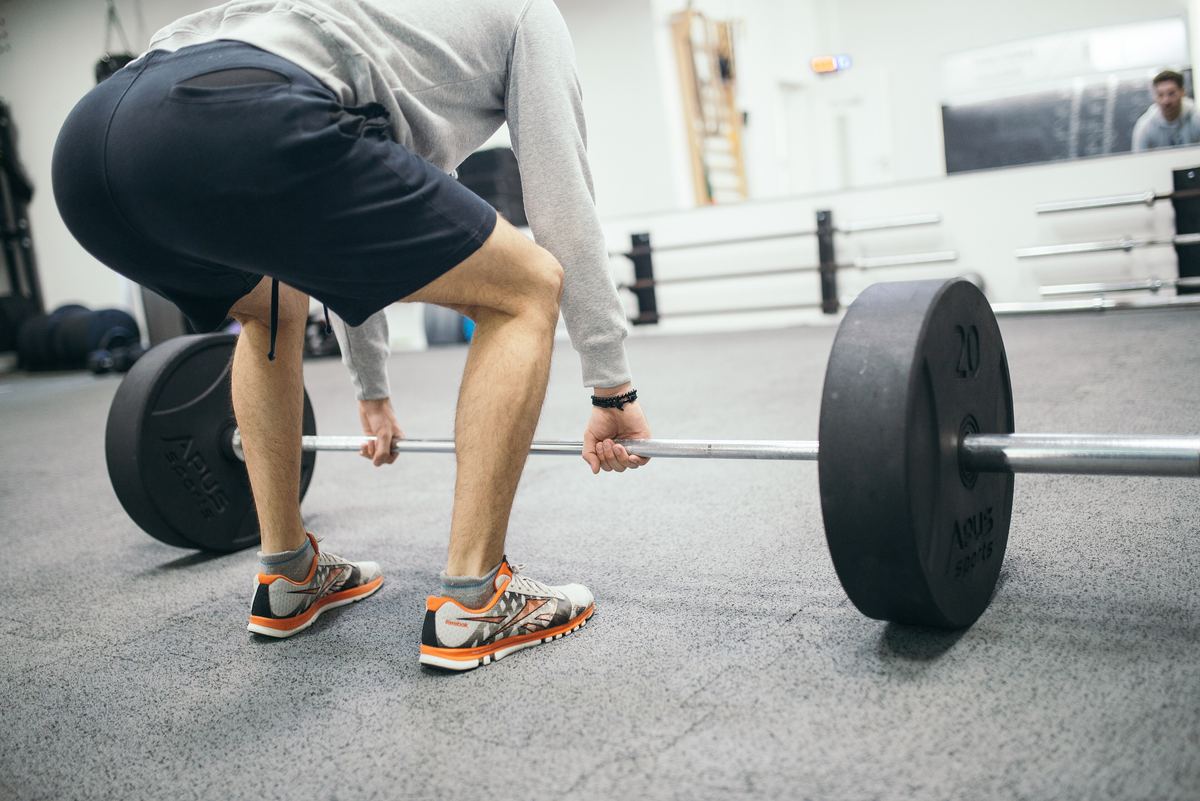 Man gripping a loaded barbell at the start of a deadlift