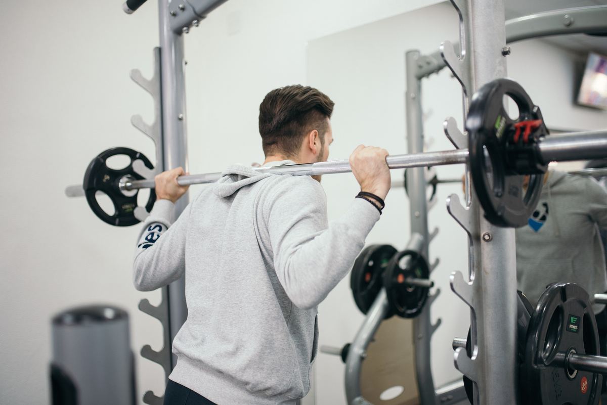 Man setting up under a loaded barbell in a squat rack at a gym