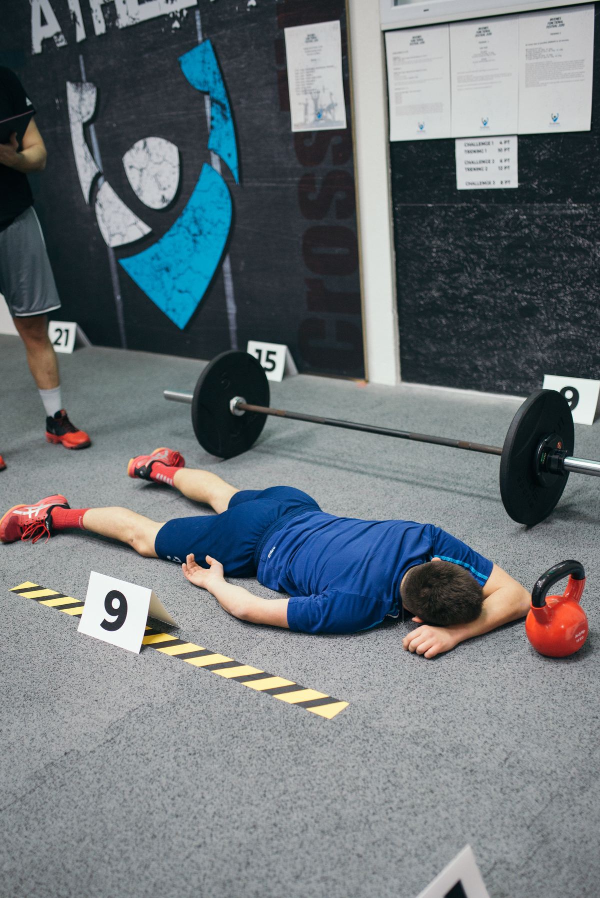 Man lying on a gym floor recovering between efforts