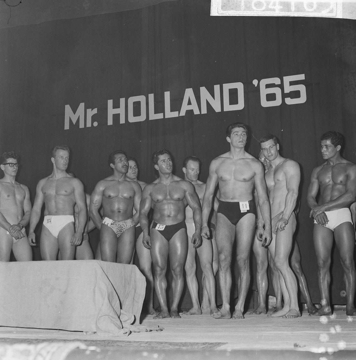 Competitors lined up on stage at the 1965 Mr. Holland bodybuilding contest in Amsterdam