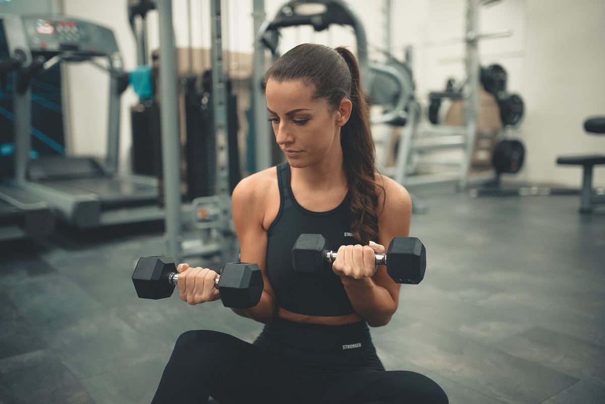 Woman sitting on the floor doing dumbbell curls